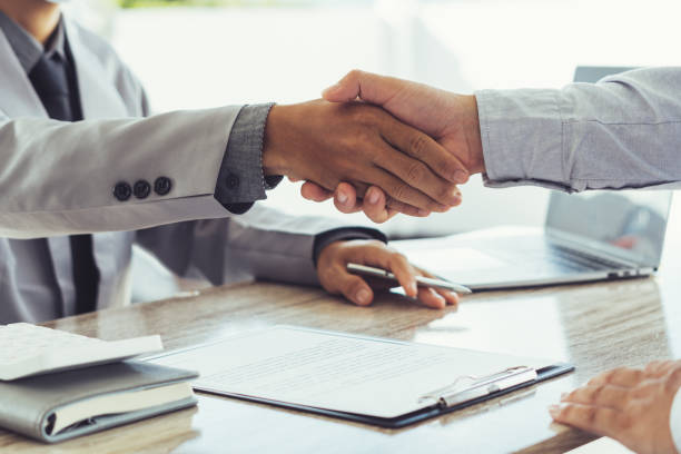 Two business people shake hands after a business deal is reached In the office area Two business people shake hands after a business deal is reached In the office area job fair stock pictures, royalty-free photos & images