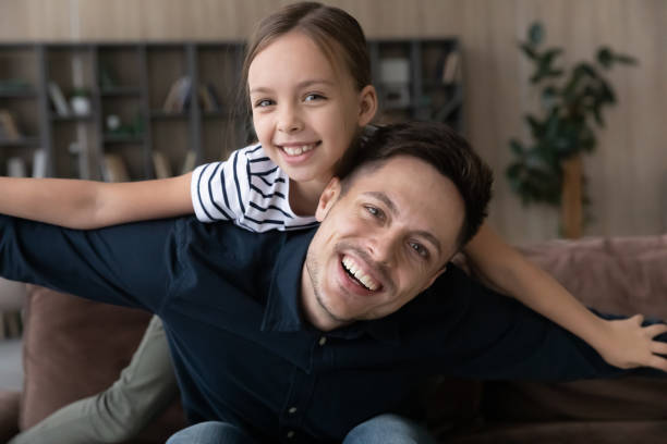 istock Daughter hangs on fathers back spread arms like plane wings 1337568699