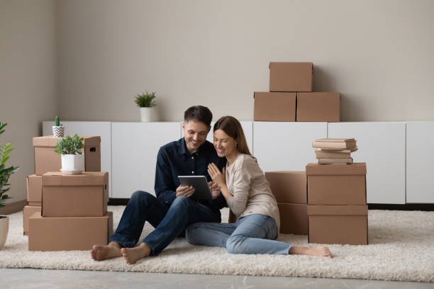 istock Couple sit on floor near boxes use tablet discuss purchase 1337568795