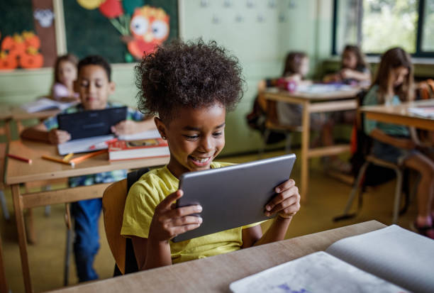 studente elementare nero felice che usa il touchpad in una classe. - digital tablet student studying learning foto e immagini stock