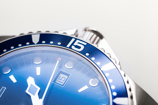 Automatic mechanical mans wrist watch fragment with blue deal, date indication and rotating ceramic bezel, Swiss made. Closeup photo with selective soft focus