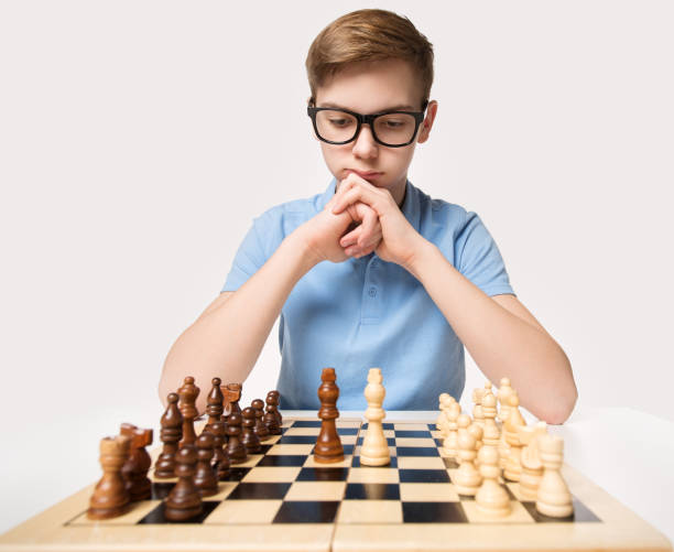 teenager spielt schachspiel. kinder lernen strategiedenken. child education concept über white studio hintergrund - concentration chess playing playful stock-fotos und bilder