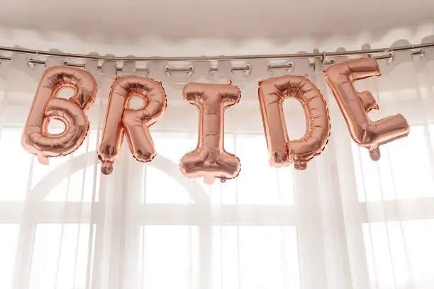 Photo of BRIDE - word made from rose gold foil balloons. party or holiday decor concept for bride at home.