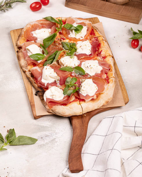 istock Italian roman rectangular pizza with prosciutto and mozzarella on wooden board on white rustic background 1337573010