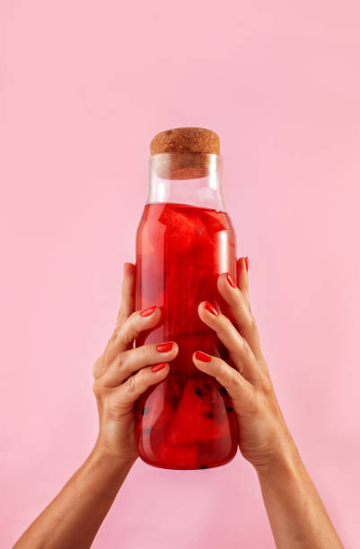 istock Femail hands holding glass bottle on pink background 1337573157