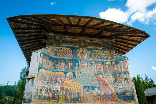 Voronet, Romania - 5 August, 2021: Color image depicting the ancient architecture and murals of Voronet monastery in the north of Romania.