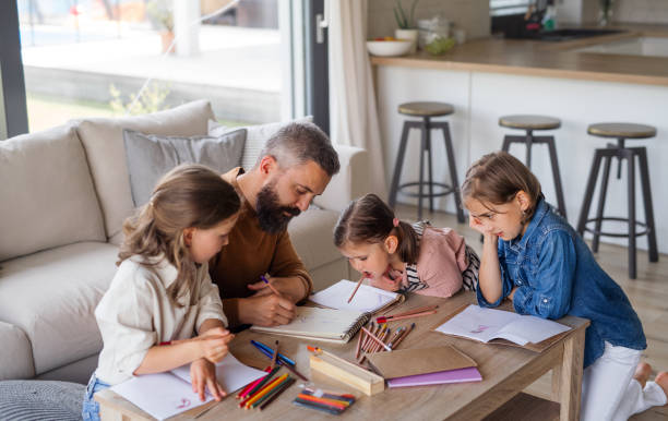 istock Father with three daughters indoors at home, drawing pictures. 1337578698