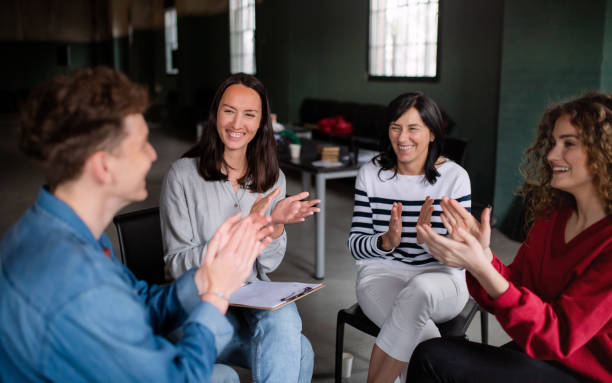 istock Joyful men and women sitting in circle during group therapy, talking and clapping. 1337578947