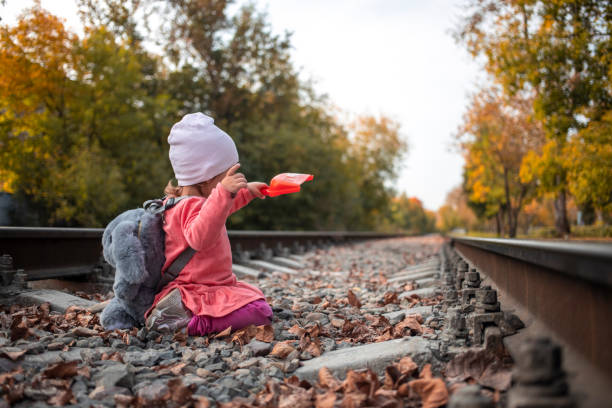 adorable petite fille jouant avec une cuillère sur les rails. jeux dangereux d’enfants - autumn table setting flower photos et images de collection