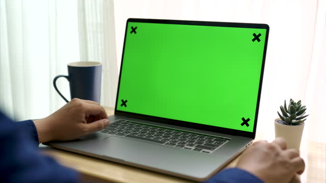 Over the shoulder shot of a young Businessman working on laptop with green screen