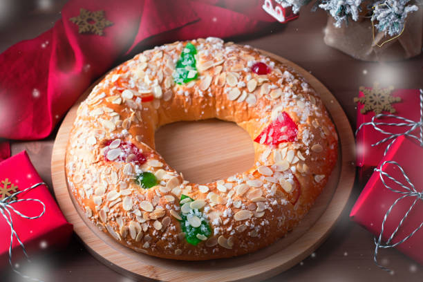 istock Traditional Epiphany cake Roscon de Reyes on wooden table top with small Christmas tree, wrapped gifts and decoration closeup, top view 1337586397