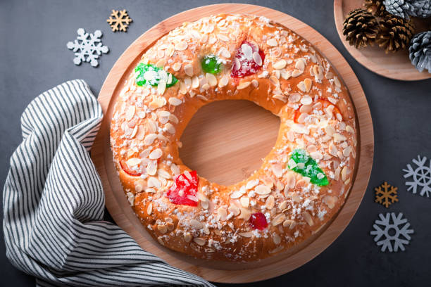 istock Traditional Epiphany cake Roscon de Reyes on grey stone table top with small Christmas tree and decoration closeup, top view 1337586405
