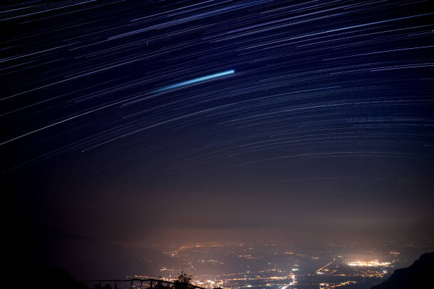 Startrail above the misty cities, night landscape, city of Gemona del Friuli, FVG region, Italy Panoramic view of the plain in FVG region under the the sky at night gemona del friuli stock pictures, royalty-free photos & images