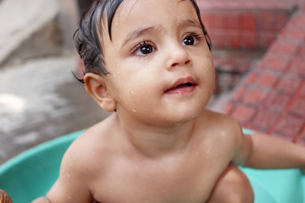 adorable niña pequeña disfrutando del agua al aire libre - baby child poverty water fotografías e imágenes de stock
