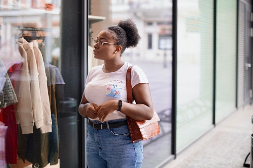 Young black woman window shopping, looking at shop window