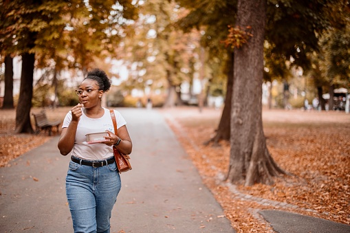 Young black woman eating organic fruit while on a walk around park