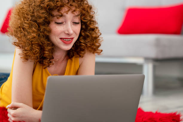 istock Young woman laying on a red pluffy carpet and using her laptop. 1337591652