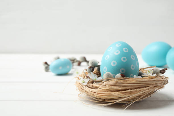 istock Colorful Easter egg in decorative nest on white wooden table. Space for text 1337595446