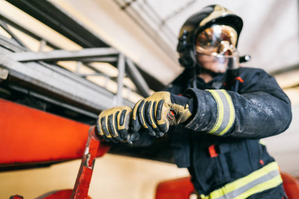 istock Anonymous firefighter in uniform with yellow lines and protective helmet moving red lever arm near ladder on fire truck in garage 1337597244