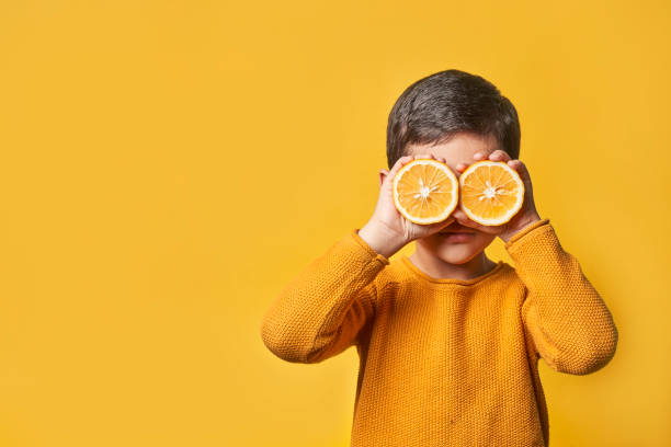 Little boy hides eyes with lemon slices