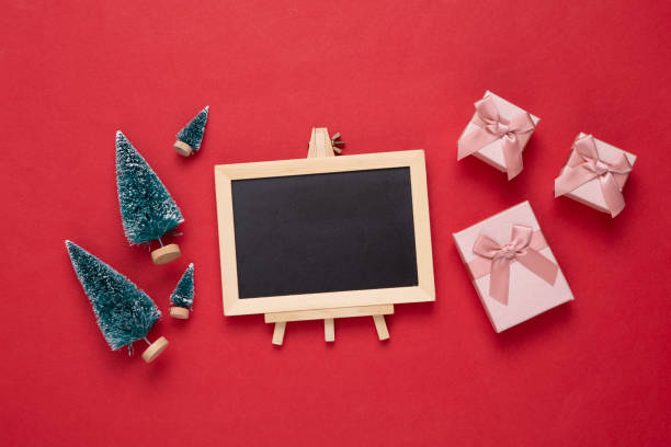 istock Mini blackboard with Christmas tree, gift boxes on red background. Empty, blank chalkboard with copy space. New year, Christmas still life 1337599567