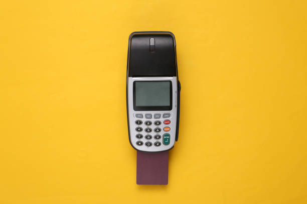istock Payment terminal with bank card on yellow background. 1337599620