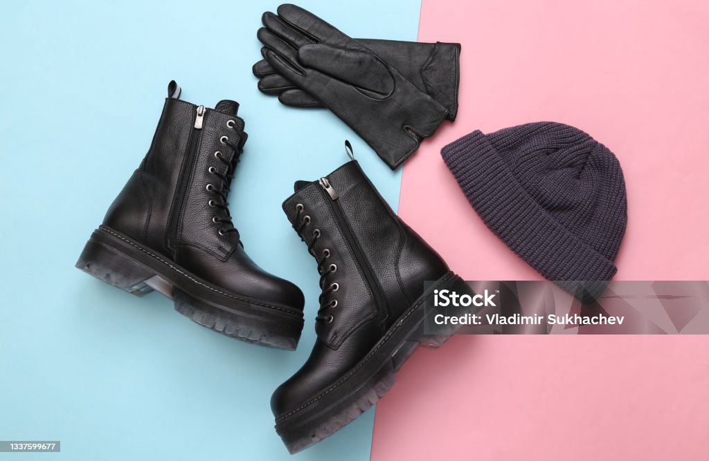 Stylish leather boots, beanie hat and gloves on blue pink pastel background Shoe Stock Photo