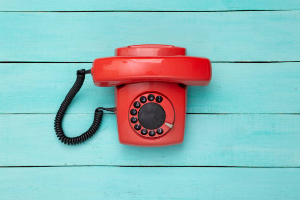 Retro red old fashioned rotary phone on blue wooden table. Top view