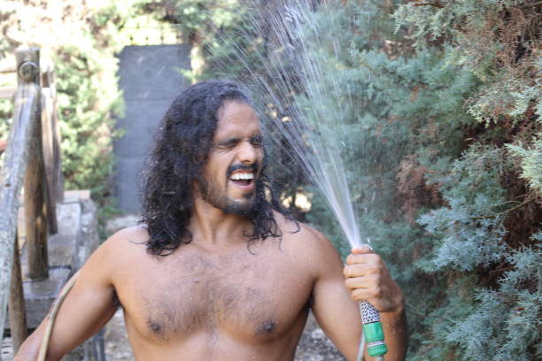 istock Seductive long haired man getting wet with hose 1337599784