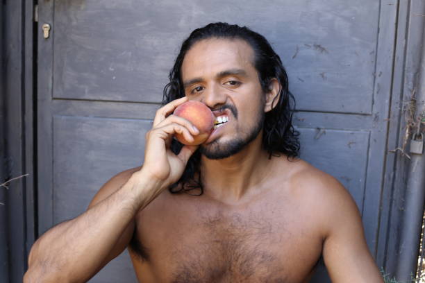 istock Attractive long haired man eating a peach 1337599811
