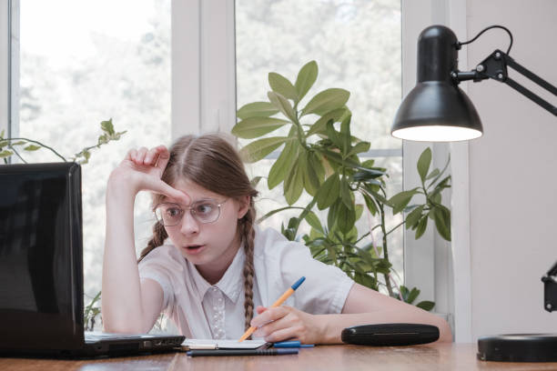 istock Schoolgirl self isolation using laptop for his homework. Gaming, education and school concept - sad girl with laptop and at home. Girl having hard time doing homework online, sitting depressed indoors 1337602212