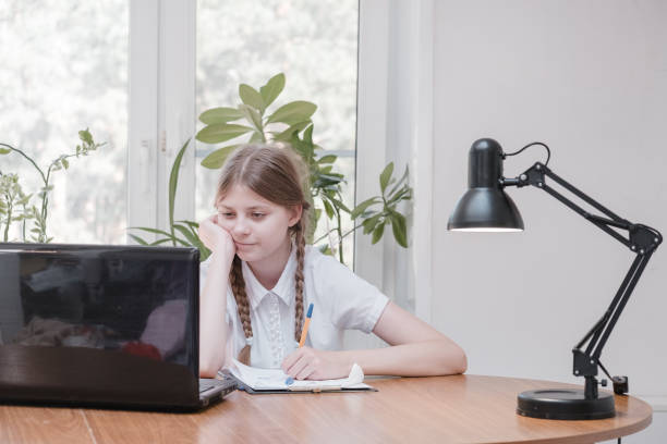 Schoolgirl self isolation using laptop for his homework. Girl doing using digital tablet searching information on internet during covid 19 lock down. Social distance, E-learning online education stock photo