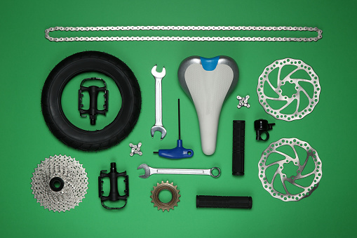 Set of different bicycle tools and parts on green background, flat lay