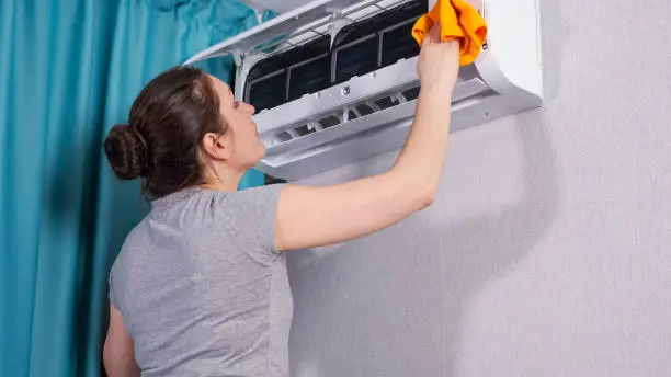 Photo of Woman sprays water on cloth and cleans air conditioner