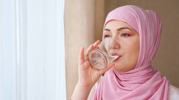 istock Young woman in hijab drinks water from a glass 1337608519