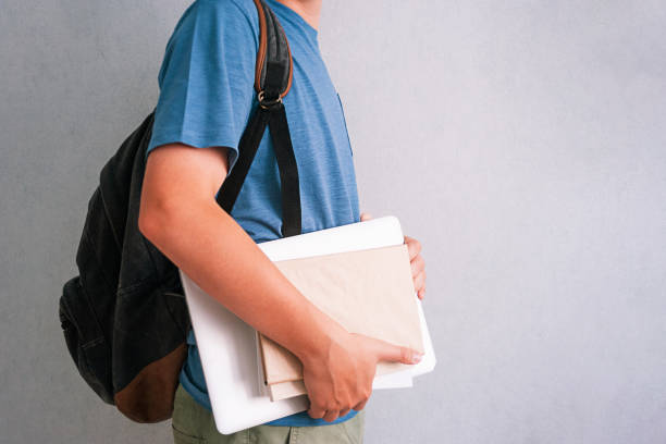 istock Teenager with backpack, textbooks and laptop on light background 1337610776