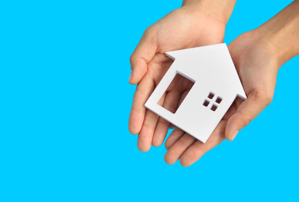 close up of hands holding house or home model on a blue background, real estate and property concept. - investment real estate construction residential structure imagens e fotografias de stock