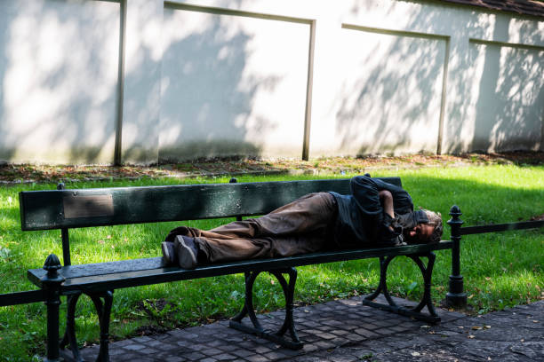 Krakow, Poland - August 29, 2018: Homeless sleeping on a bench in a park in Krakow, Poland