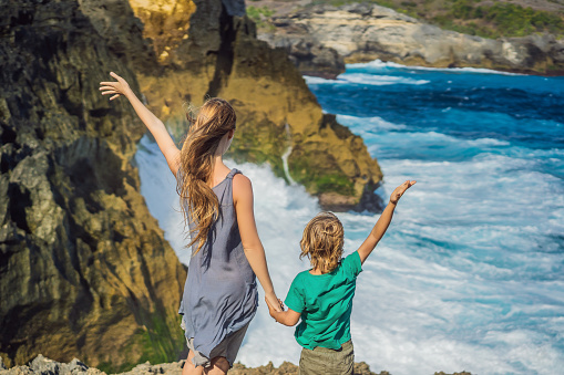 mother and son tourists against the background of the sea Angel's Billabong in Nusa Penida, Bali, Indonesia. Travel to Bali with kids concept.