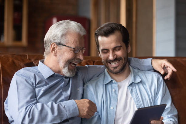 istock Smiling old dad and adult son use tablet at home 1337616377