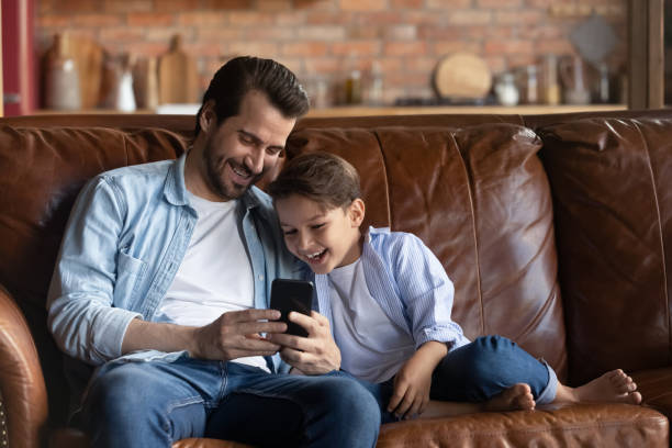 istock Happy little boy and dad use smartphone at home 1337616416