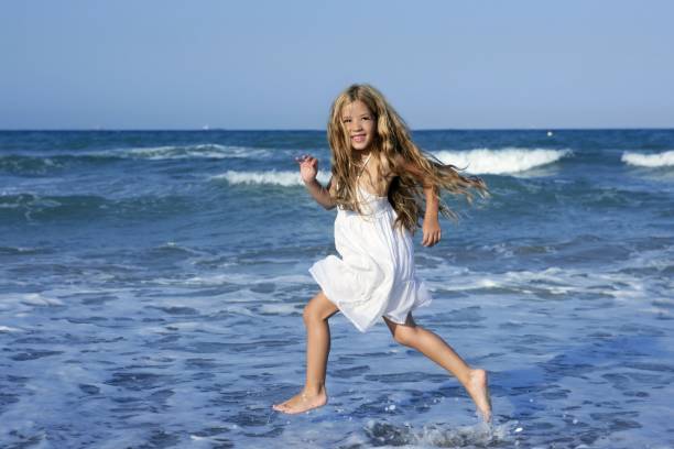 istock Little girl running beach in blue sea 1337620236