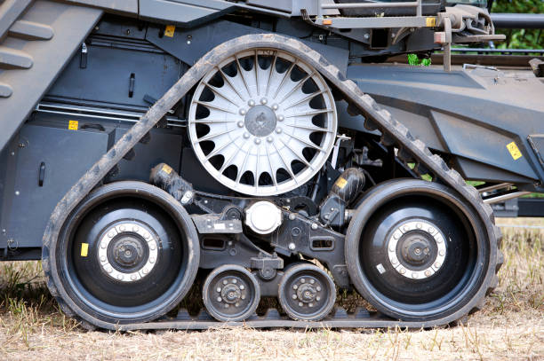 Combine Harvester harvesting agricultural machinery equipment showing triangular arrangement of tracked bogey wheel assembly in field