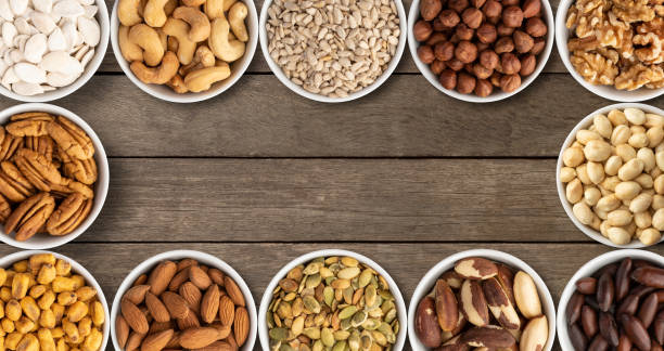 istock Assorted nuts and seeds in bowls over wooden table with copy space 1337623348