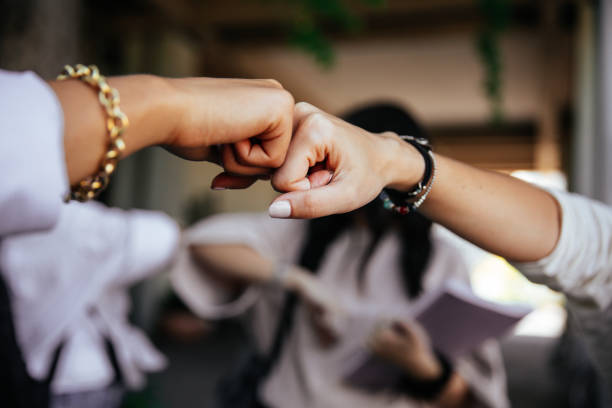 Group of students friends meet and greet out of school after class. Elbow and fist bumps