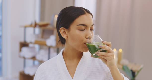 scatto di una giovane donna che si gode un drink salutare in una spa - smoothie drinking women drink foto e immagini stock