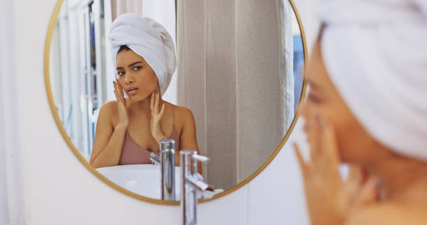 aufnahme einer attraktiven jungen frau, die ihr gesicht im badezimmerspiegel inspiziert - mirror women looking human face stock-fotos und bilder