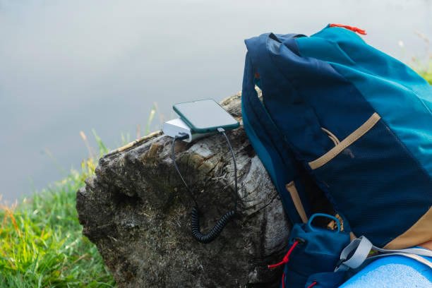 istock Smartphone is charged using a portable charger. Power Bank charges the phone outdoors with a backpack for tourism in the background of nature and the river. 1337626580