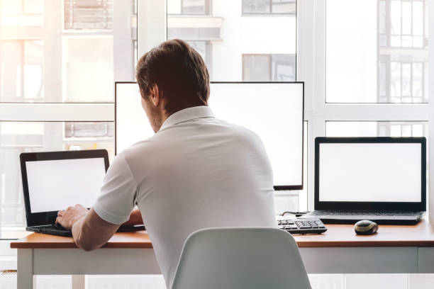istock Man at workplace with two laptops and monitor 1337627692