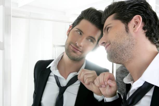 Handsome narcissistic young man looking in a mirror stock photo